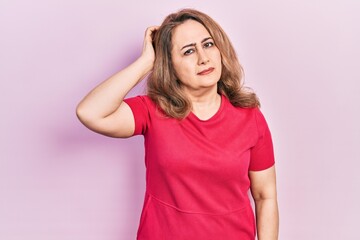 Fototapeta premium Middle age caucasian woman wearing casual clothes confuse and wondering about question. uncertain with doubt, thinking with hand on head. pensive concept.