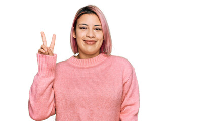 Hispanic woman with pink hair wearing casual winter sweater smiling looking to the camera showing fingers doing victory sign. number two.