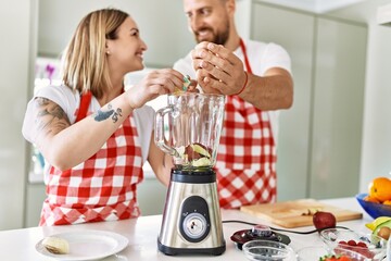 Young couple smiling confident making smoothie cooking at kitchen