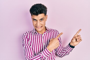 Young hispanic man wearing casual clothes pointing aside worried and nervous with both hands,...
