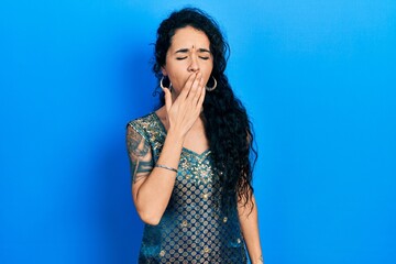 Young woman wearing bindi and traditional kurta dress bored yawning tired covering mouth with hand....