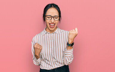 Young hispanic girl wearing casual clothes and glasses celebrating surprised and amazed for success...