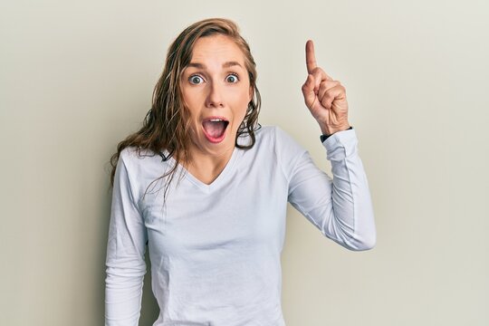 Young blonde woman wearing casual clothes pointing finger up with successful idea. exited and happy. number one.