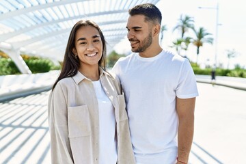 Young latin couple smiling happy and hugging at the city.