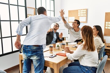 Two workers smiling happy high five during meeting at the office.