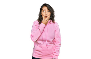 Young hispanic woman wearing casual sweatshirt looking fascinated with disbelief, surprise and amazed expression with hands on chin
