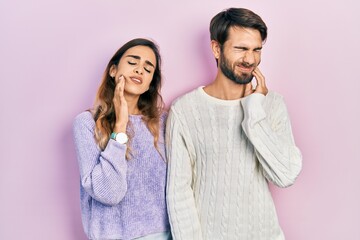 Young hispanic couple wearing casual clothes touching mouth with hand with painful expression because of toothache or dental illness on teeth. dentist