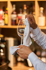 Waiter serving the table.Closeup of empty glass for wine, plate on the white tablecloth against...