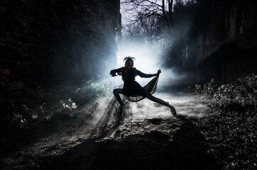 A young witch dances and conjures on Halloween night in smoke and light at the festival of the dead.