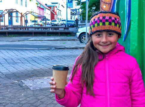 Fototapeta Closeup shot of a caucasian girl holding a coffee in the streets of Italy