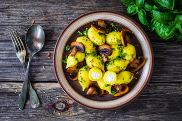 Gnocchi stuffed with cheese and fried white mushrooms on wooden table
