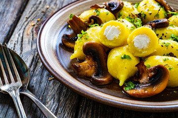 Gnocchi stuffed with cheese and fried white mushrooms on wooden table
