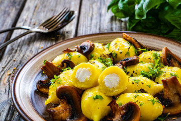 Gnocchi stuffed with cheese and fried white mushrooms on wooden table
