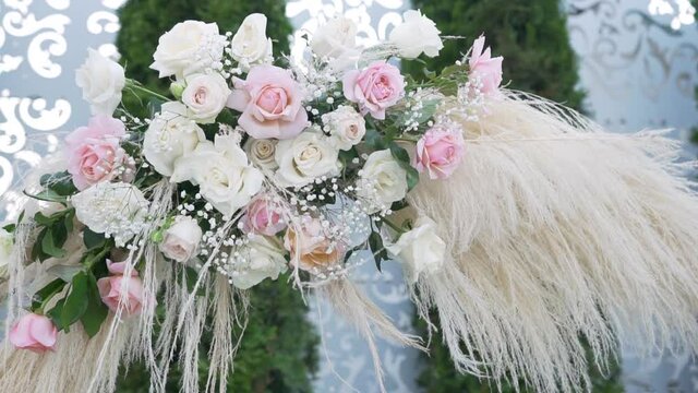 Floral arrangements are decorated by a florist. Buds on the stems of fresh rose and gypsophila and dried cane flowers adorn the metal structures of the holiday arch. Wedding arch in vintage style