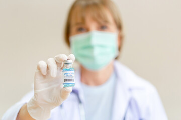 Close up of female doctor wearing medical protective face mask holding COVID-19 vaccine, Healthcare and Medical concepts