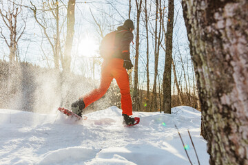 Snowshoeing outdoor winter fitness activity happy man running in snowshoes in snow from behind in...