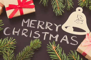 Inscription Merry Christmas, wrapped gifts, bell shape and spruce branches. Decoration for christmas time
