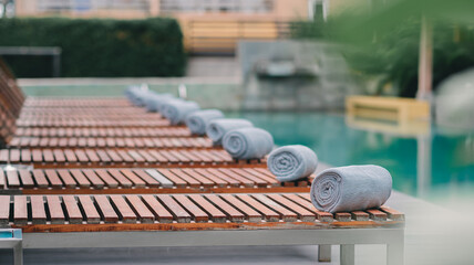 The towels are meticulously laid out on the wooden poolside beds, Vacationing in a hotel or resort,...