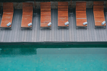 The wooden beds and towels are meticulously laid out poolside, Vacationing in a hotel or resort,...