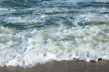 Beautiful seascape with beautiful sea waves and sea foam on shore with sea water on beach by sea