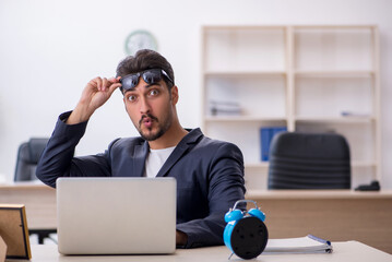 Young handsome employee in time management concept