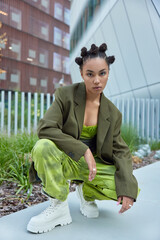 Photo of stylish serious teenage girl dressed in green formal jacket loose trousers and white boots...
