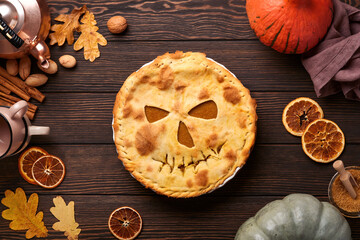 Halloween food. Homemade pumpkin pie or tart with a scary face for Halloween on a wooden table. Copy space. Halloween food concept.