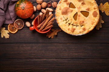 Obraz na płótnie Canvas Halloween food. Homemade pumpkin pie or tart with a scary face for Halloween on a wooden table. Copy space. Halloween food concept.