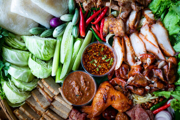 Isan food set. GRILLED PORK WITH PICKLED FISH SAUCE and spicy sauce. Fresh vegetables and chili Surf on the banana leaf in wooden tray