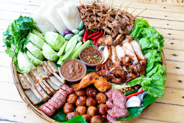 GRILLED PORK WITH PICKLED FISH SAUCE and spicy sauce. Fresh vegetables and chili Surf on the banana leaf in wooden tray