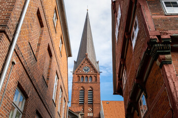 der Turm einer Kirche am Ende der Gasse zwischen  zwei Backsteinhäusern