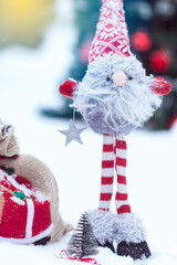 Snowy handmade dwarf close up in red white clothes with bag of gifts in decorated Christmas tree...