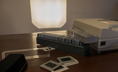 antique white slide projector seen from the side, from above with the slides scattered, the light...