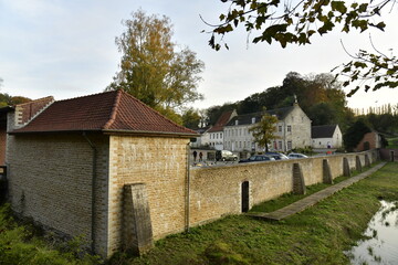 Fototapeta na wymiar Mur d'enceinte et les bâtiments de l'abbaye du Rouge-Cloître avec sa cour servant de parking en pleine forêt de Soignes à Auderghem