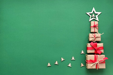 Christmas tree made from wrapped gift boxes with red ribbons with a wooden star on a green...