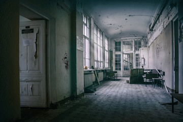 Naklejka premium A beautiful corridor in an old abandoned hospital. Sunlight in the windows. Shabby walls and doors. Old architecture of an abandoned building.