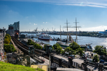 Fototapeta premium Hamburg harbor, Germany: Beautiful panoramic view of the harbor with Elbe on a sunny day with blue sky in summer, St. Pauli district, train station Landungsbruecken