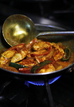 cocinando pollo y verduras con salsa curry en sart&eacute;n con cazo grande