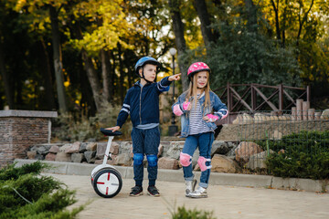 Happy Boy and girl stand and ride in the Park on Segways and scooters during sunset. Happy...