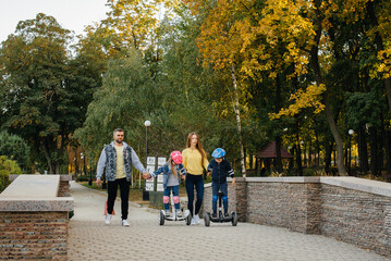 A large happy family rides Segways and electric scooters in the Park on a warm autumn day during sunset. Family vacation in the Park.