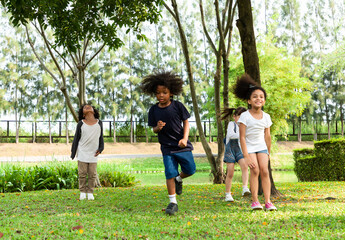 Fototapeta premium Group of diversity kids playing cheerful in the park. Children having fun and jumping with rope in the garden.