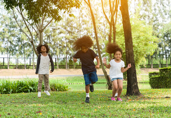 Fototapeta premium Group of diversity kids playing cheerful in the park. Children having fun and jumping with rope in the garden.