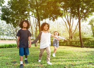 Fototapeta premium Group of diversity kids playing cheerful in the park. Children having fun and jumping with rope in the garden.