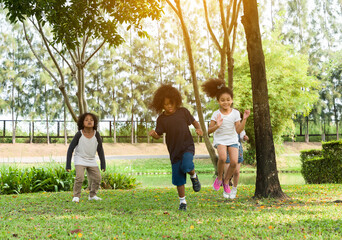 Fototapeta premium Group of diversity kids playing cheerful in the park. Children having fun and jumping with rope in the garden.