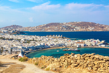 Mykonos town port with red churches, famous windmills, ships and yachts during summer sunny day. Aegean sea, Greece