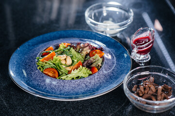 Prepare a delicious fresh salad of tomato greens, cheese, veal and cashew nuts. Delicious healthy food.