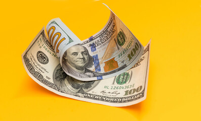 One hundred dollar bills closeup on yellow background
