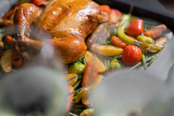 Festive dinner for two of chicken and vegetables. baking sheet with baked chicken and baked green beans, baby carrots, potatoes, green peppers and Brussels sprouts. two glasses of wine.