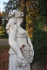 Fototapeta premium statue of a girl with flowers and grapes in a basket half-naked greek sculpture