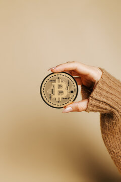 Woman's hand holding golden bitcoin on pastel beige background. Creative cryptocurrency or blockchain concept. Stock Market, digital gold money and stock business.